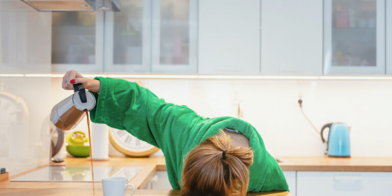 Tired woman sleeping on the table in the kitchen at breakfast. T